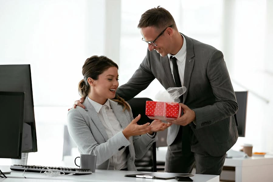 Hombre dando un regalo a su compañera de oficina